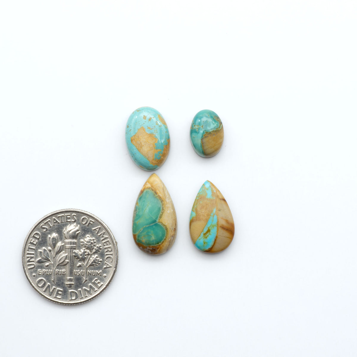 Kings Manassa Turquoise cabochons, polished green-blue gemstones with natural matrix on a white background with a US dime for scale