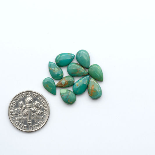 Kings Manassa Turquoise cabochons, polished green-blue gemstones with natural matrix on a white background with a US dime for scale
