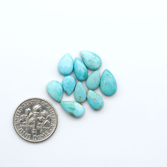 Kings Manassa Turquoise cabochons, polished green-blue gemstones with natural matrix on a white background with a US dime for scale