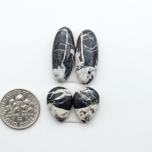 White Buffalo stone cabochons, white stone with black matrix, polished stones on a white background, with a US dime for scale