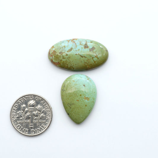 Turquoise Mountain Turquoise cabochons, polished blue and green gemstones with natural matrix on a white background with a US dime for scale