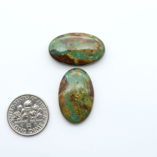 Turquoise Mountain Turquoise cabochons, polished blue and green gemstones with natural matrix on a white background with a US dime for scale