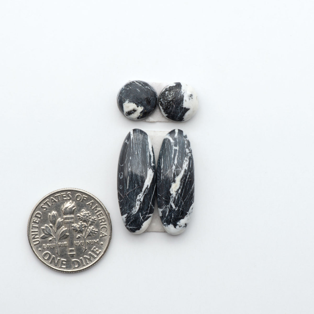 White Buffalo stone cabochons, white stone with black matrix, polished stones on a white background, with a US dime for scale