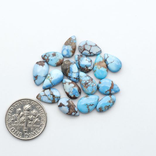Golden Hills Turquoise cabochons, icy blue to lavender tones with chocolate matrix, polished stones on a white background with a US dime for scale