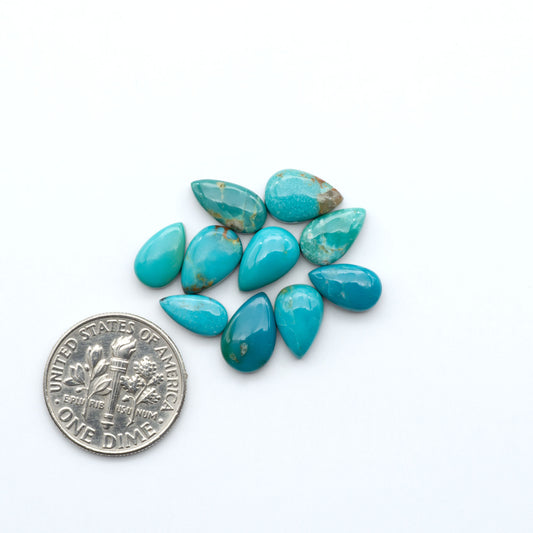 Kings Manassa Turquoise cabochons, polished green-blue gemstones with natural matrix on a white background with a US dime for scale