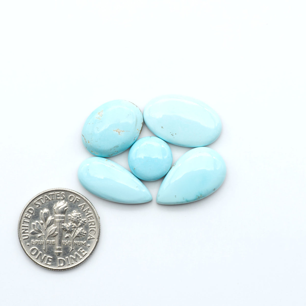 Royston Turquoise cabochons, blue-green color with natural matrix, polished stones on a white background, with a US dime for scale