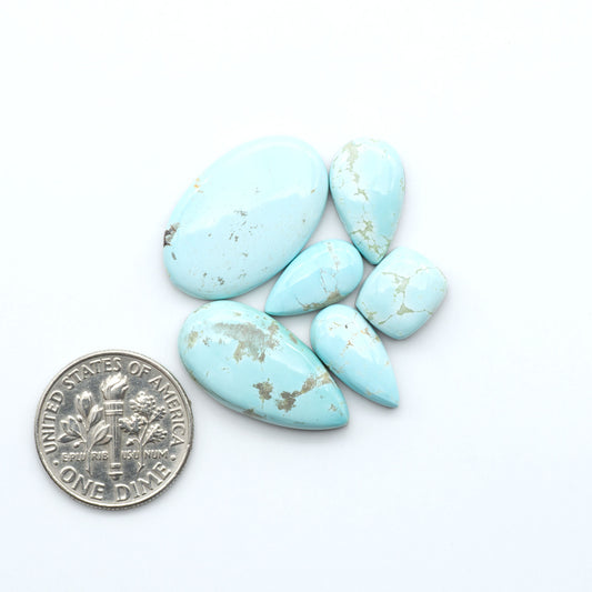 Royston Turquoise cabochons, blue-green color with natural matrix, polished stones on a white background, with a US dime for scale