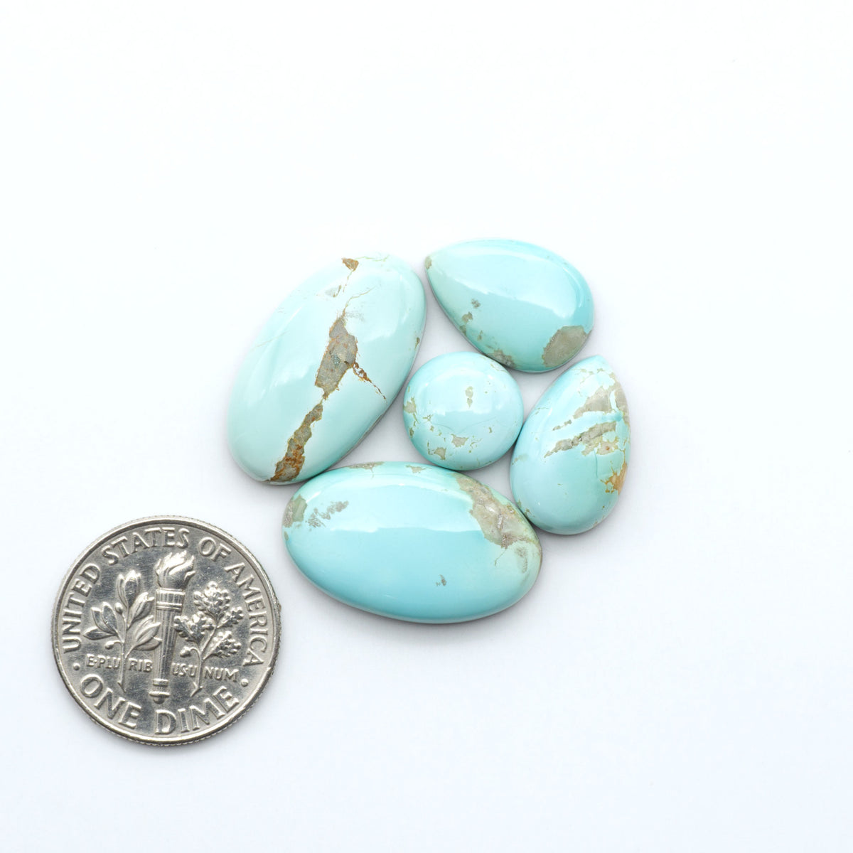 Royston Turquoise cabochons, blue-green color with natural matrix, polished stones on a white background, with a US dime for scale