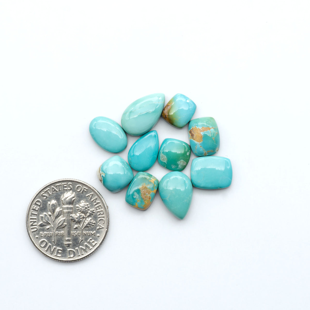 Royston Turquoise cabochons, blue-green color with natural matrix, polished stones on a white background, with a US dime for scale