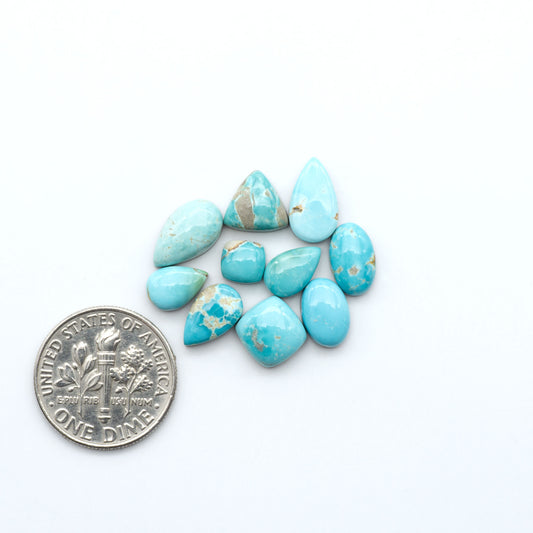 Royston Turquoise cabochons, blue-green color with natural matrix, polished stones on a white background, with a US dime for scale
