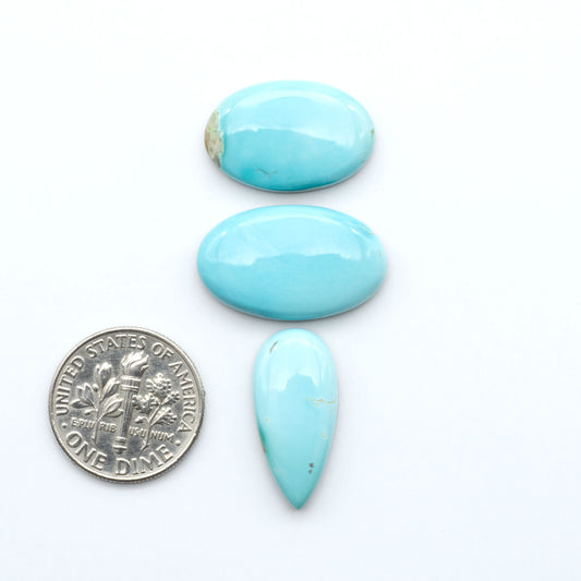 Royston Turquoise cabochons, blue-green color with natural matrix, polished stones on a white background, with a US dime for scale