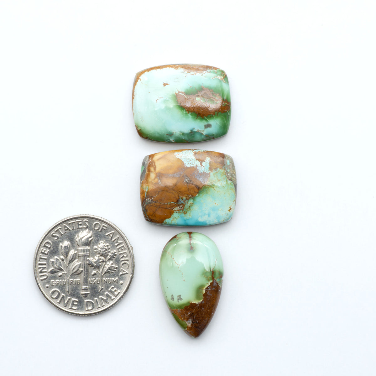 Royston Turquoise cabochons, blue-green color with natural matrix, polished stones on a white background, with a US dime for scale