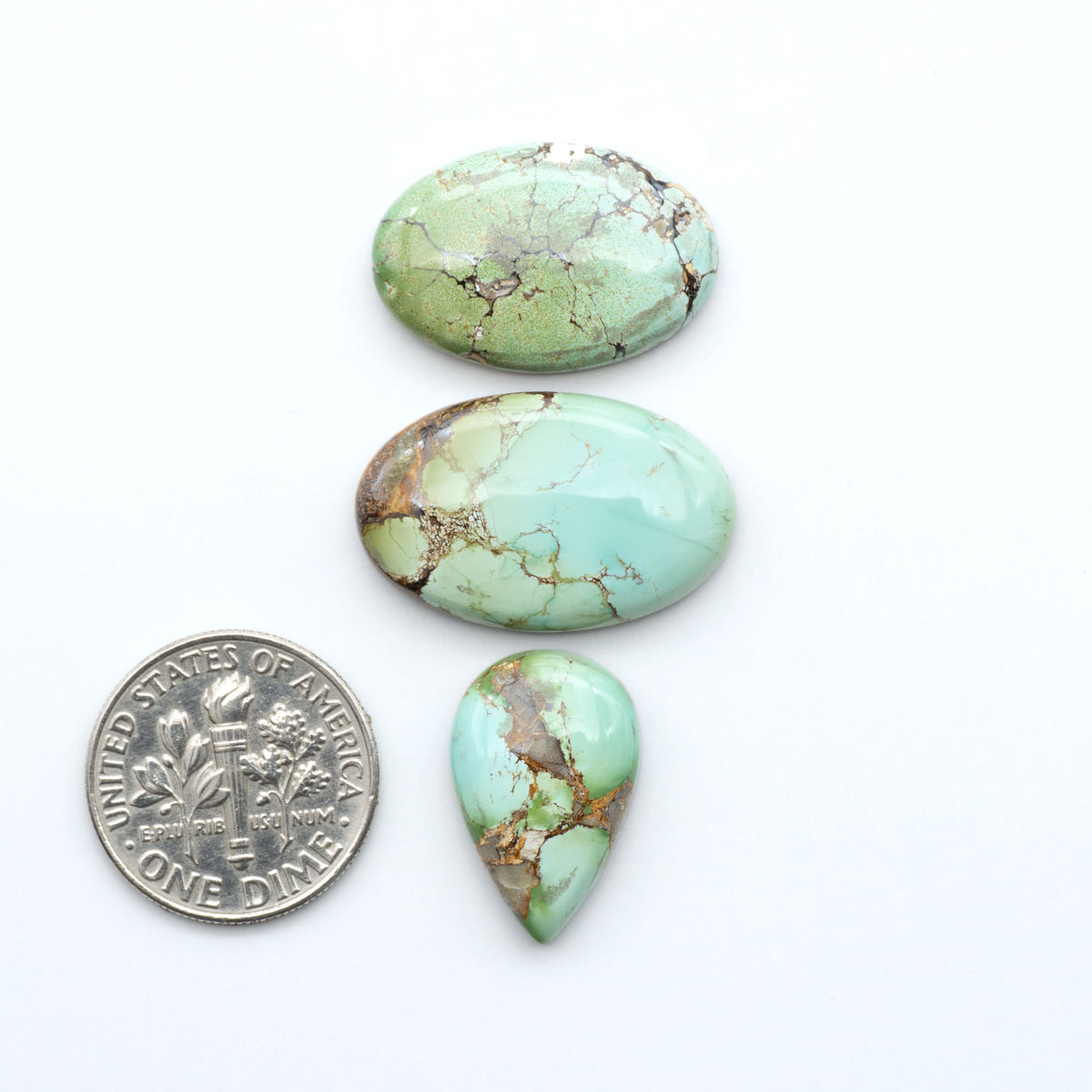 Royston Turquoise cabochons, blue-green color with natural matrix, polished stones on a white background, with a US dime for scale