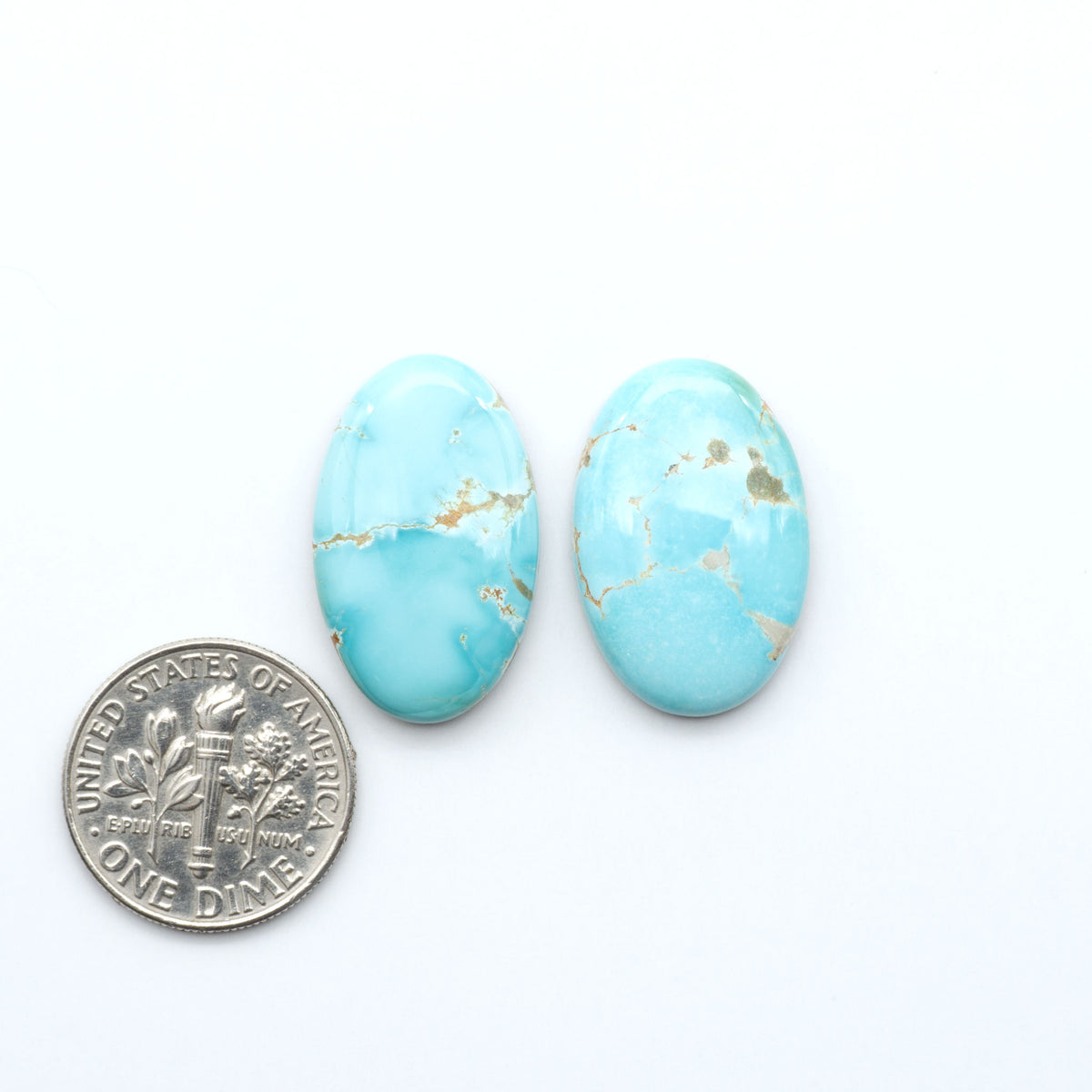 Royston Turquoise cabochons, blue-green color with natural matrix, polished stones on a white background, with a US dime for scale