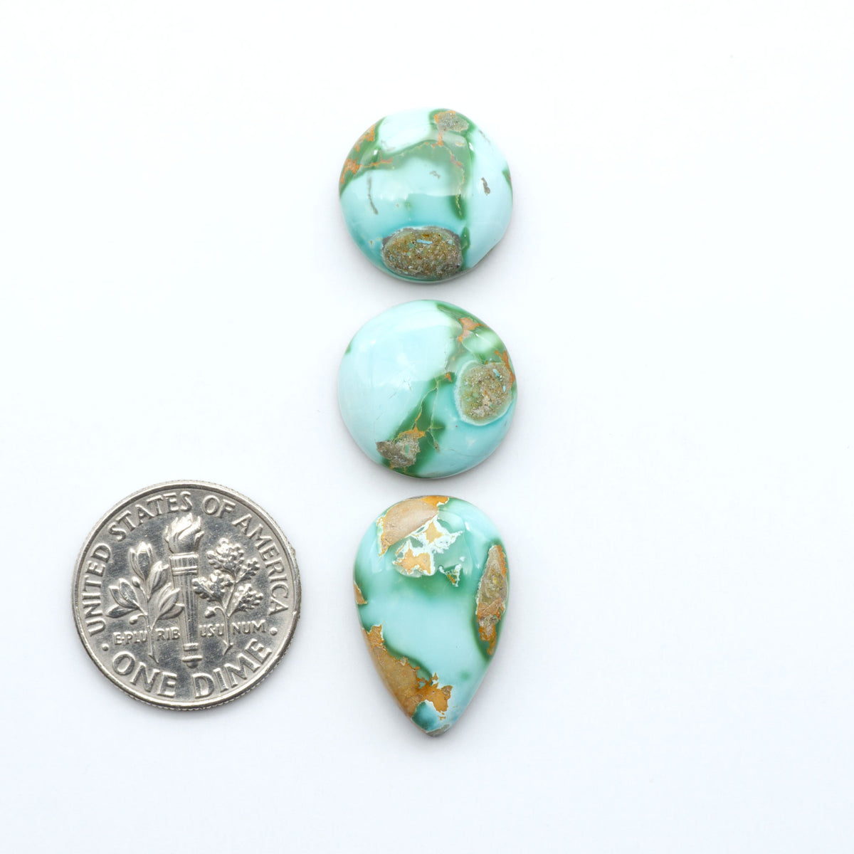 Royston Turquoise cabochons, blue-green color with natural matrix, polished stones on a white background, with a US dime for scale