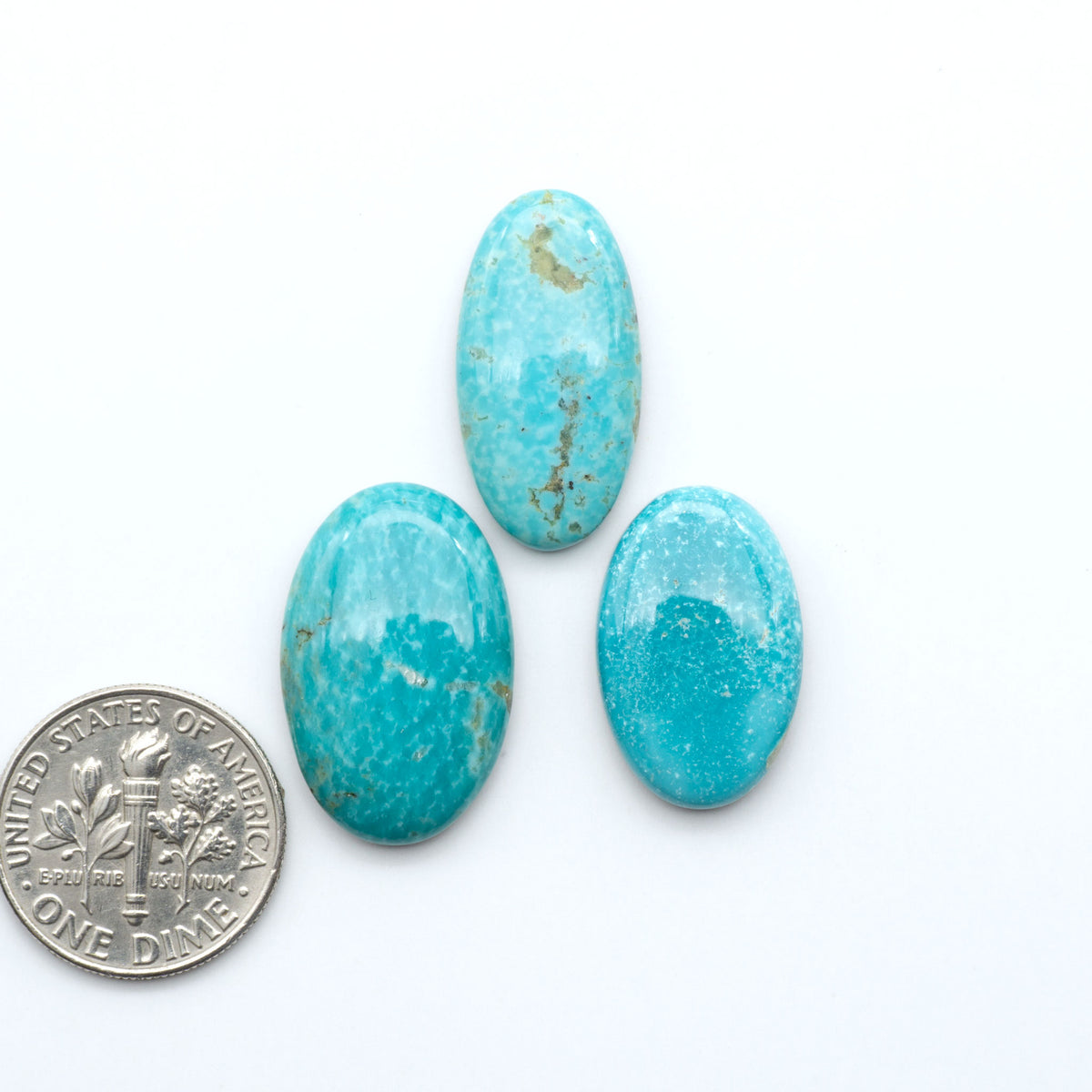Royston Turquoise cabochons, blue-green color with natural matrix, polished stones on a white background, with a US dime for scale