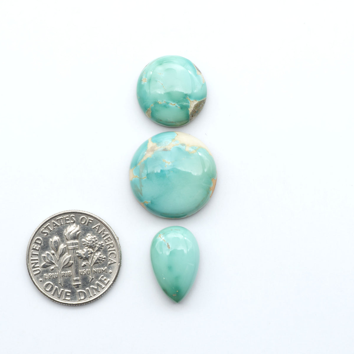 Royston Turquoise cabochons, blue-green color with natural matrix, polished stones on a white background, with a US dime for scale
