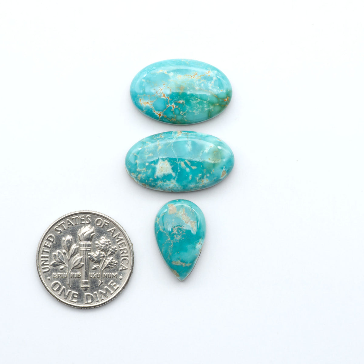 Royston Turquoise cabochons, blue-green color with natural matrix, polished stones on a white background, with a US dime for scale