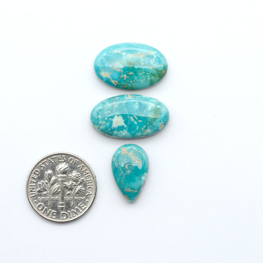 Royston Turquoise cabochons, blue-green color with natural matrix, polished stones on a white background, with a US dime for scale