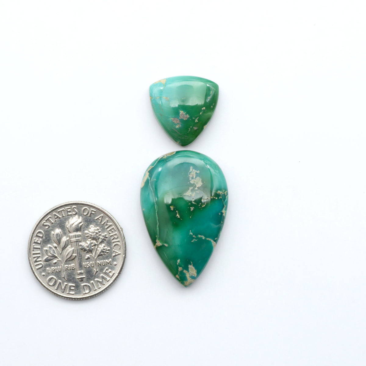 Royston Turquoise cabochons, blue-green color with natural matrix, polished stones on a white background, with a US dime for scale