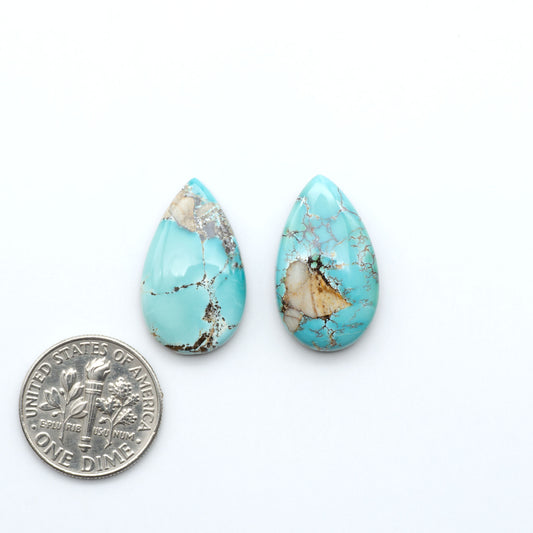 Royston Turquoise cabochons, blue-green color with natural matrix, polished stones on a white background, with a US dime for scale