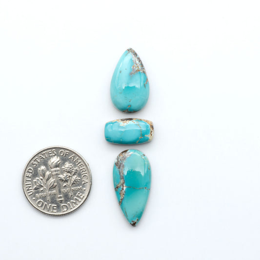 Royston Turquoise cabochons, blue-green color with natural matrix, polished stones on a white background, with a US dime for scale