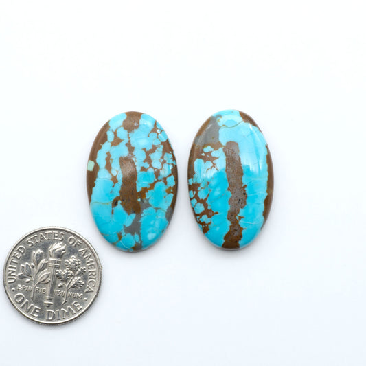 Number 8 Turquoise cabochons, blue and green color with brown matrix, polished stones on a white background, with a US dime for scale